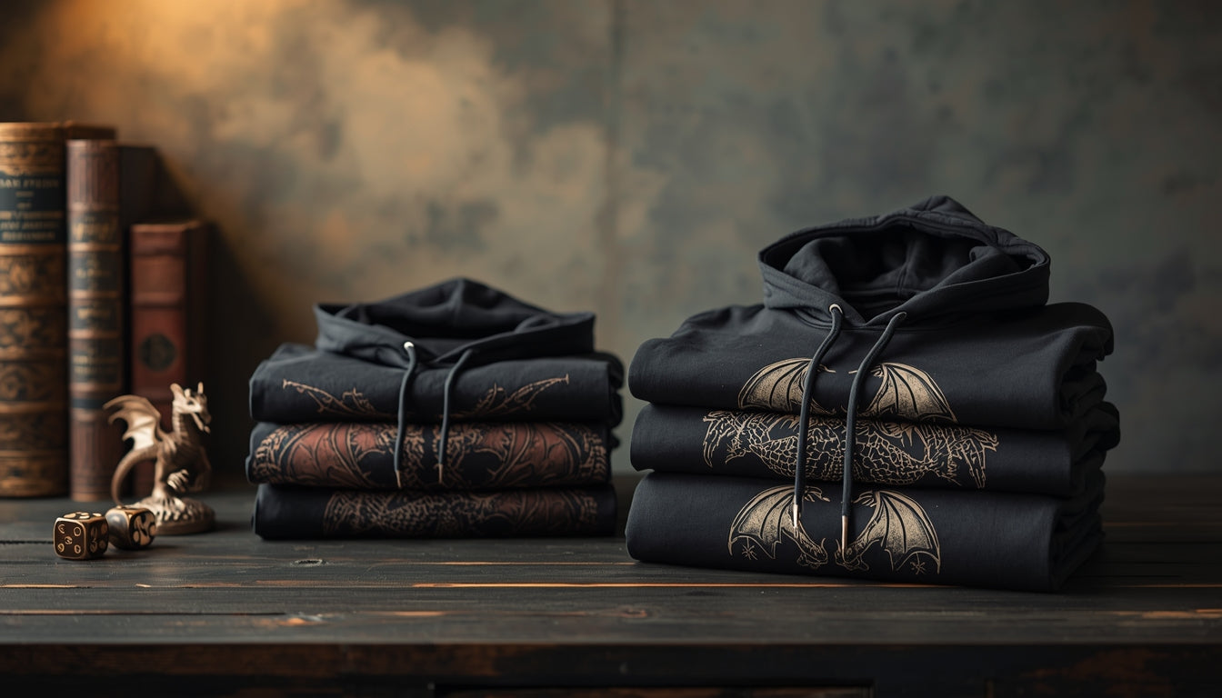Folded dragon graphic hoodies stacked on a wooden table with subtle fantasy props under warm cinematic lighting.