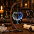 Anne Stokes Dragon Heart Ornament displayed on a wooden stand in a fantasy library surrounded by books, crystals and candlelight.