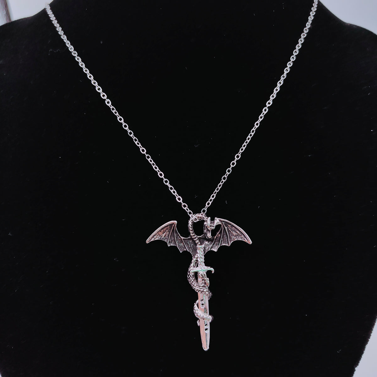Silver-tone dragon sword pendant necklace displayed on black jewellery bust