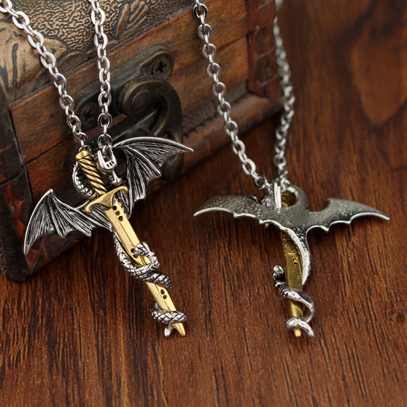Silver and gold dragon sword pendant necklaces displayed beside a wooden chest