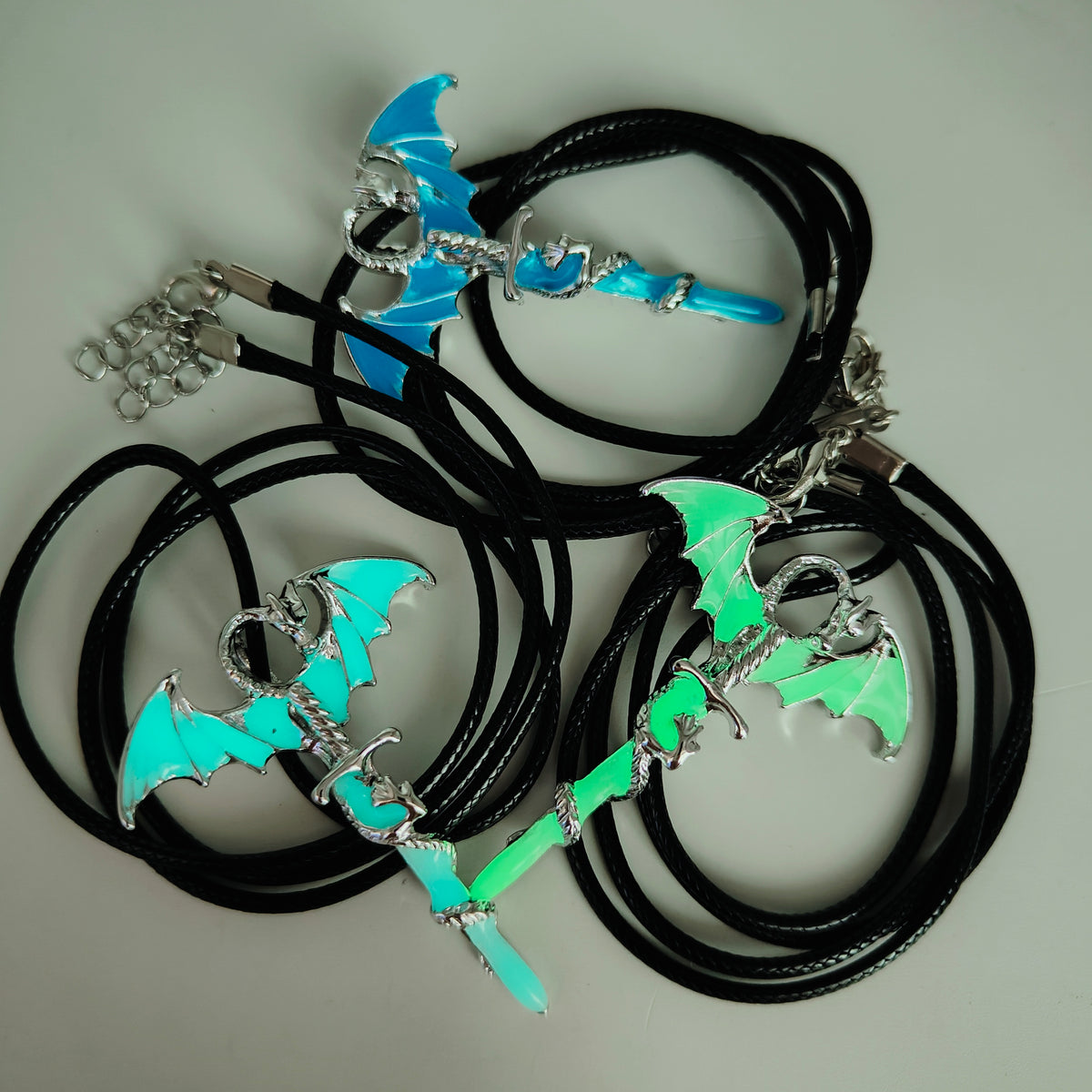 Glow in the dark dragon sword necklaces in blue, light blue and green
