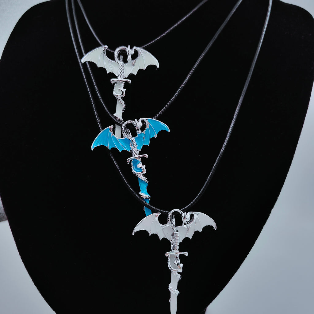 Three dragon sword necklaces with black cords arranged on white background
