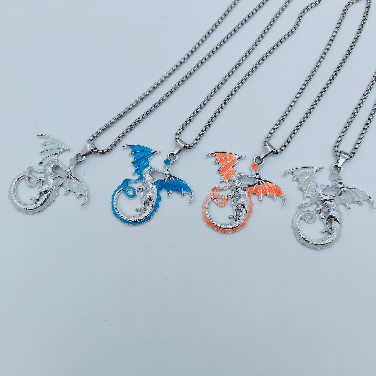 Four colour variations of the flying dragon pendant necklace