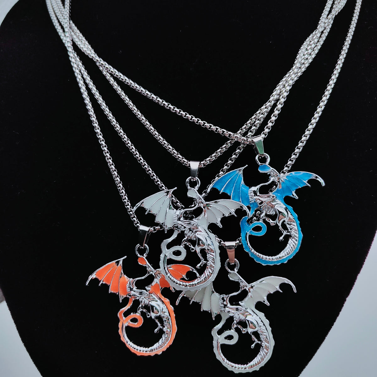 Flying dragon necklaces displayed together on black jewellery stand
