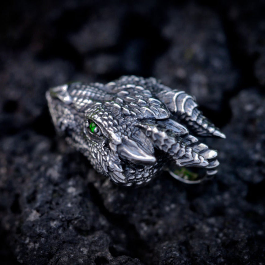Angled view of antique silver dragon pendant with sculpted horns and textured scales