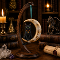 Lisa Parker black cat moon ornament with snowflake details displayed on a wooden stand in a warm fantasy collector's study.