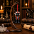 Lisa Parker black cat reindeer Christmas ornament displayed on a wooden stand in a candlelit fantasy collector's study.