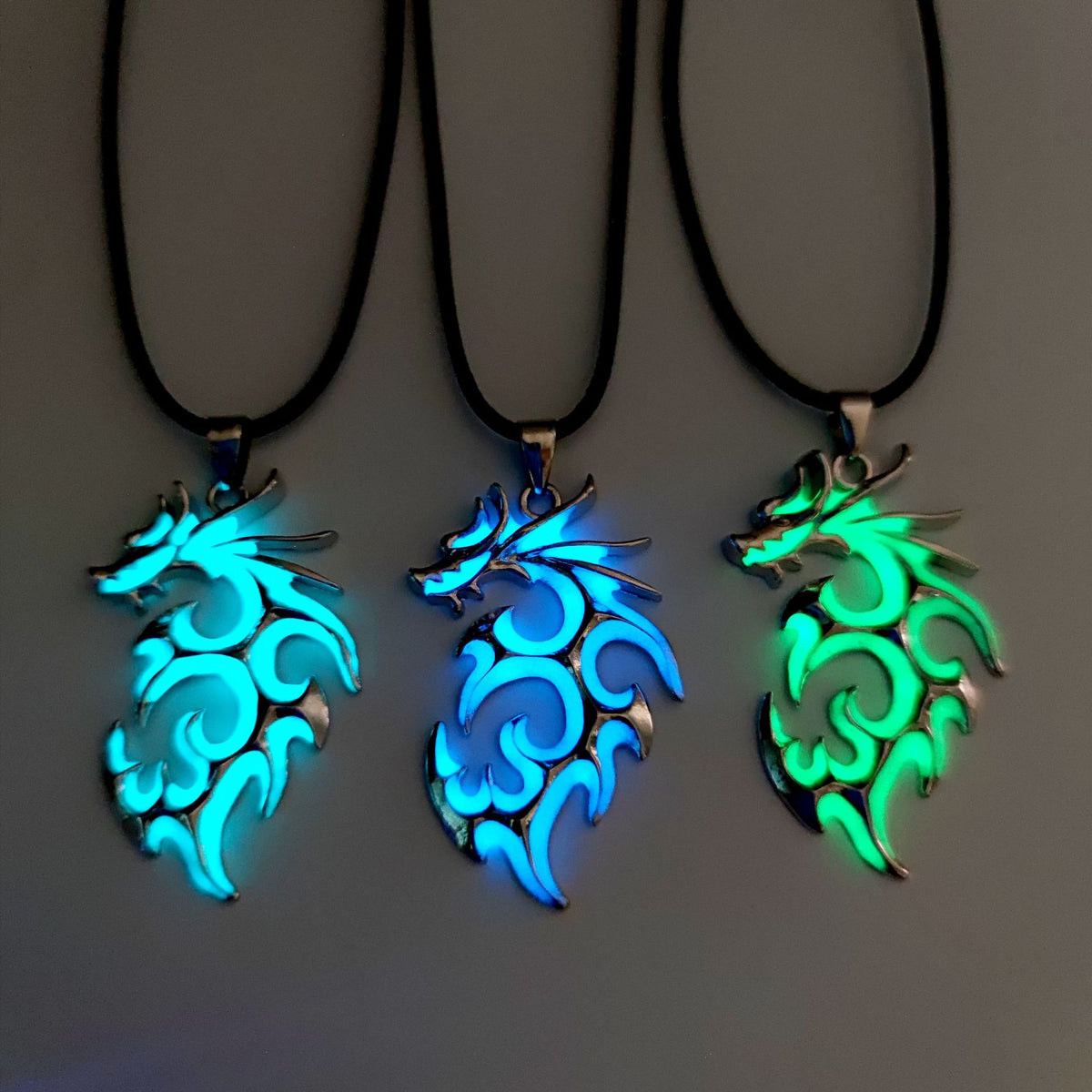 Glow in the dark dragon pendants illuminated in blue, aqua and green